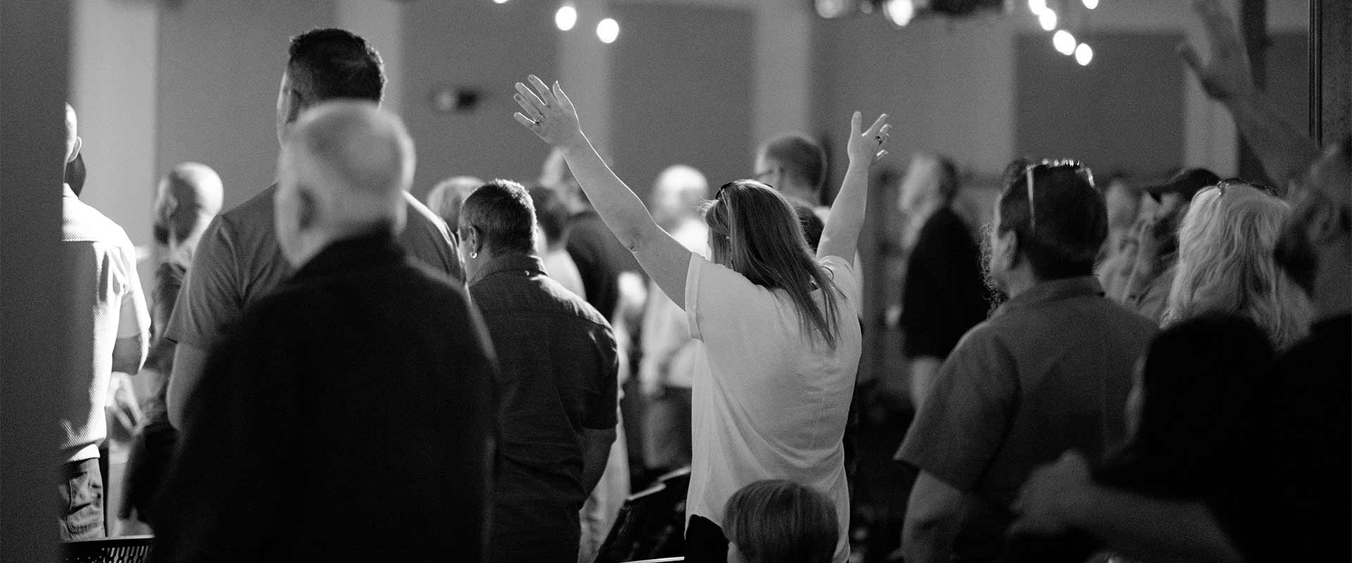 woman raising hands worshiping at church