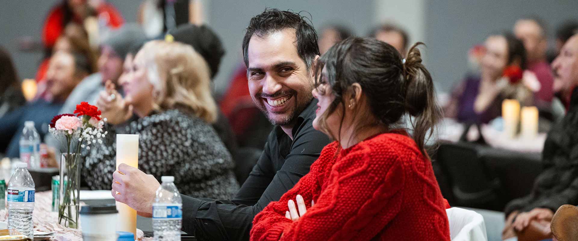married couple smiling at each other at a group event